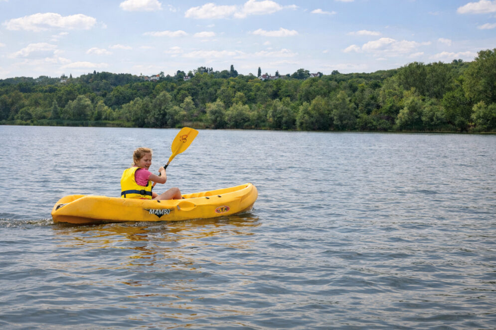 Petite fille dans un kayak jaune sur l'étang de la base de Jabines.