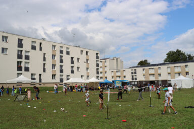 Groupe d'enfants et d'adolescents qui jouent sur un terrain de football à plusieurs jeux sur la place du Couchant à Lizy-sur-Ourcq.