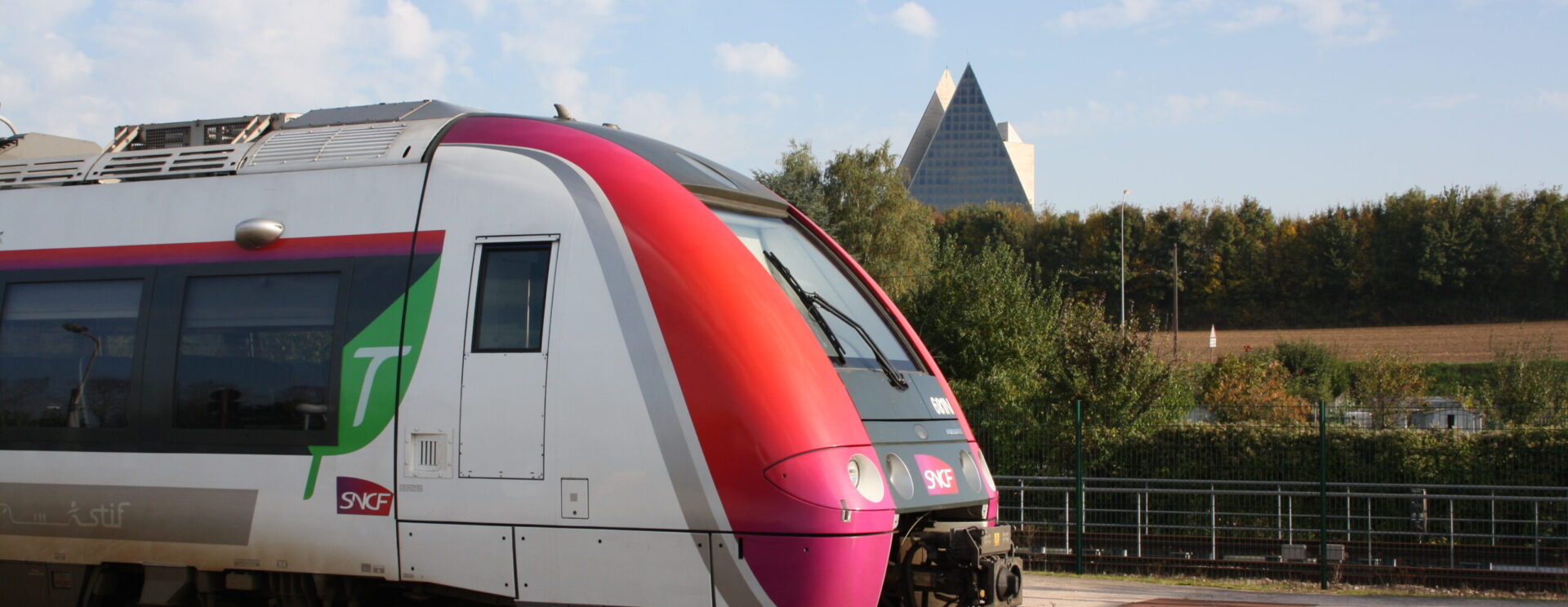 Zoom d'un train SNCF à la gare de Lizy-sur-Ourcq avec la Pyramide Jean DIDIER à Mary-sur-Marne en arrière plan