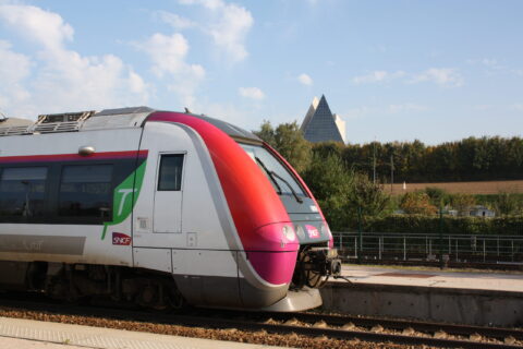 Zoom d'un train SNCF à la gare de Lizy-sur-Ourcq avec la Pyramide Jean DIDIER à Mary-sur-Marne en arrière plan