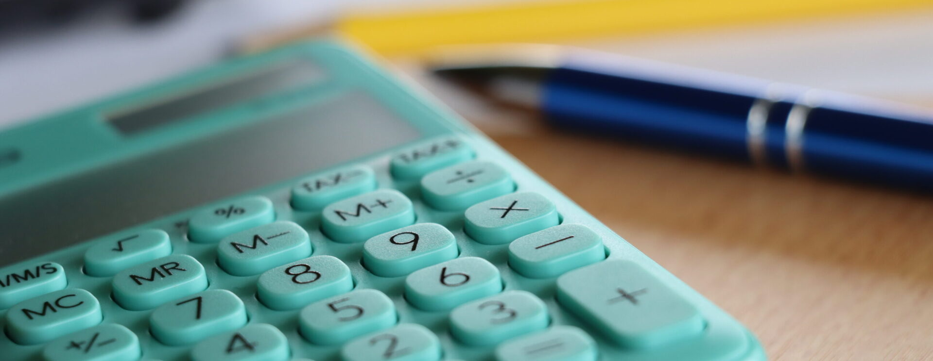 Zoom sur une calculatrice avec un stylo et crayon de papier en arrière-plan
