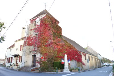 batiment d'angle en pierre avec horloge en haut de la façade. un monument avec le drapeau français y est collé. Du lierre recouvre la majeure partie de la façade. - Agrandir l'image 1 sur 6, fenêtre modale