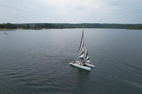 Vue aérienne d'un groupe d'enfants sur un catamaran lors des Vac'enSports à la base de loisirs de Jablines