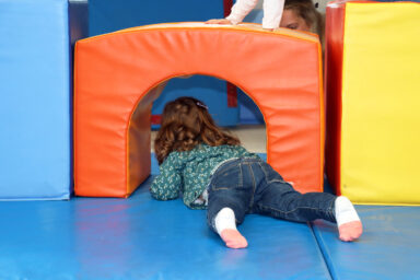 Enfant de dos au sol lors d'un ateliers Relais Petite Enfance à la salle Polyvalente de la Maison des Enfants du Pays de l'Ourcq à Ocquerre