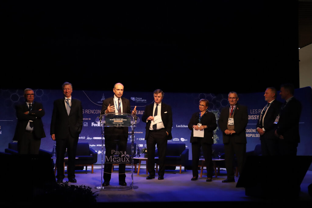 Vue de Jean-François COPÉ parlant au micro sur scène avec d'autres personnes à ses côtés lors du colloque hydrogène au Colisée de Meaux. - Agrandir l'image, fenêtre modale