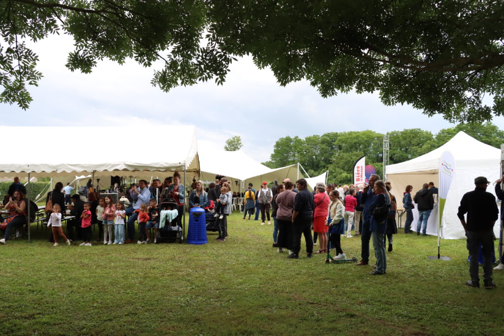 Le public installé un peu partout sur l'herbe, au cœur du village du festival, lors de la première édition du Festival Orucq'N Jazz 2024 - Agrandir l'image, fenêtre modale
