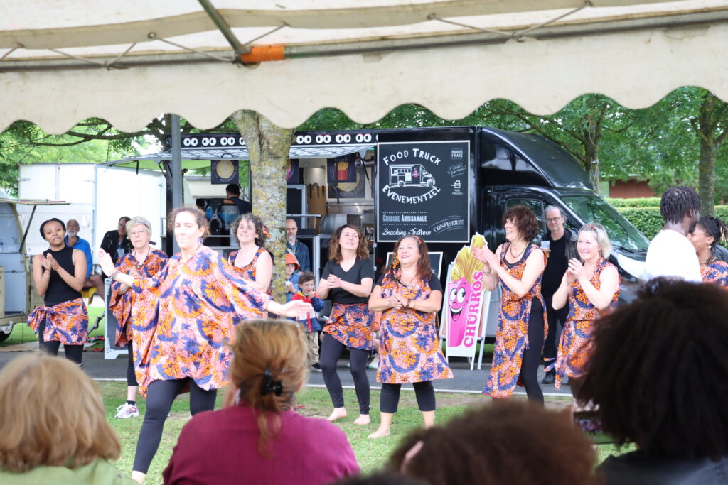 Les élèves de l'association YAMA YIGUI, le public qui les regarde, et à l'arrière-plan les food trucks lors de la 1ère édition du Festival Ourcq'N Jazz 2024 - Agrandir l'image, fenêtre modale